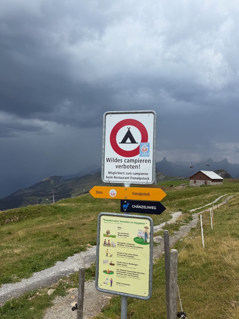 Ein Schild unterhalb des Fronalpstock-Gipfels mit durchgestrichenem Zelt und der Aufschrift Wildes campieren verboten, darunter der Hinweis auf die Campiermöglichkeit beim Restaurant Fronalpstock.