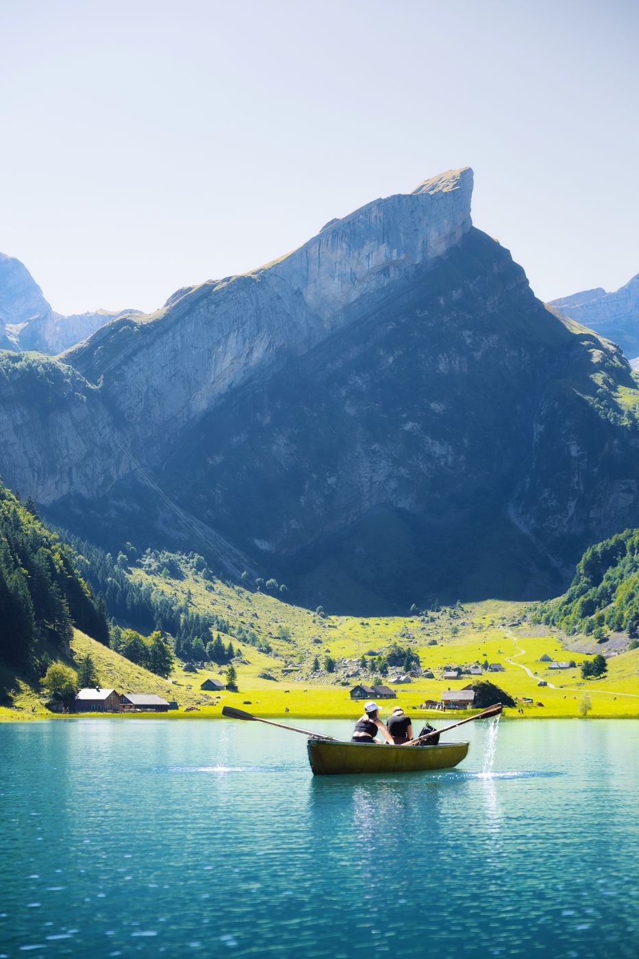 A rowing boat on the turquoise Seealpsee below the steep peaks of the Alpstein.