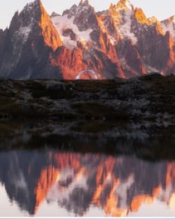 Red-lit peaks reflected in a still alpine lake