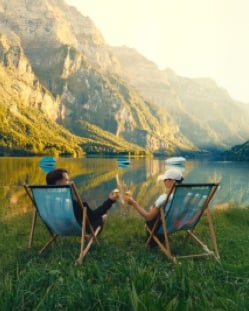 Two deckchairs on the grass above a turquoise lake
