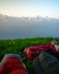 Sleeping bags out on a flowering meadow above the valley