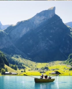 A rowing boat on a lake below a limestone face
