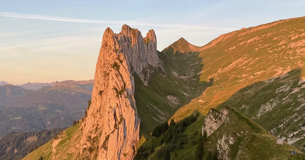 Alpenglow on the Saxer Luecke in the Alpstein, a small tent pitched on the grass below the ridge.